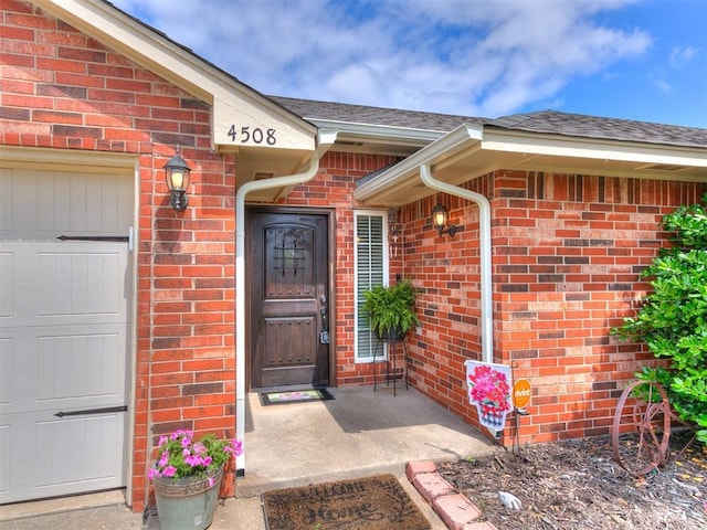 4508 Applegate Dr, Moore, OK 73160 - doorway to property featuring brick siding, roof with shingles, and an attached garage