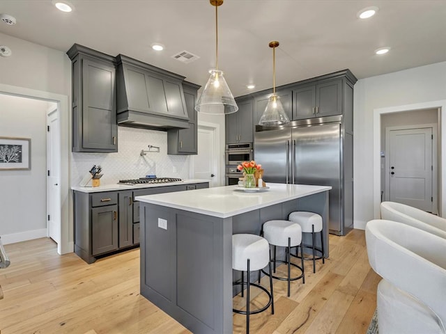 4315 Dusty Trl, Norman, OK 73072 - kitchen featuring custom exhaust hood, appliances with stainless steel finishes, light wood-type flooring, backsplash, and light countertops