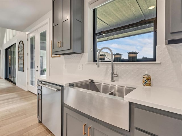 4315 Dusty Trl, Norman, OK 73072 - kitchen with gray cabinets, stainless steel dishwasher, a sink, backsplash, and light countertops