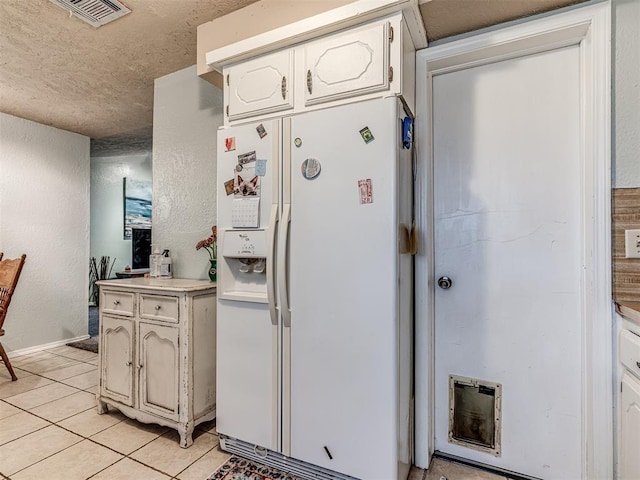 11379 Kirkwin Ln, Choctaw, OK 73020 - kitchen with white refrigerator with ice dispenser, light tile patterned floors, a textured ceiling, a textured wall, and light countertops