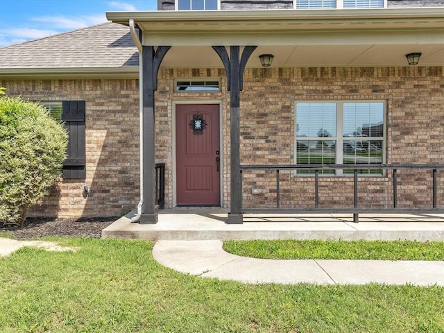 10740 Starboard Way, Edmond, OK 73025 - doorway to property with brick siding, covered porch, and a shingled roof