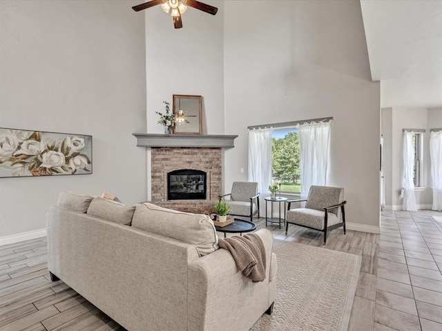 10740 Starboard Way, Edmond, OK 73025 - living room featuring a towering ceiling, a ceiling fan, a fireplace, and light wood-style floors