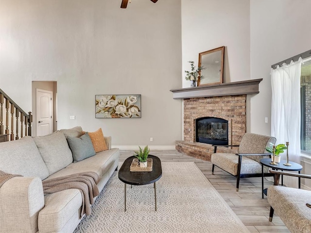 10740 Starboard Way, Edmond, OK 73025 - living room with a towering ceiling, wood finished floors, a brick fireplace, a ceiling fan, and stairs