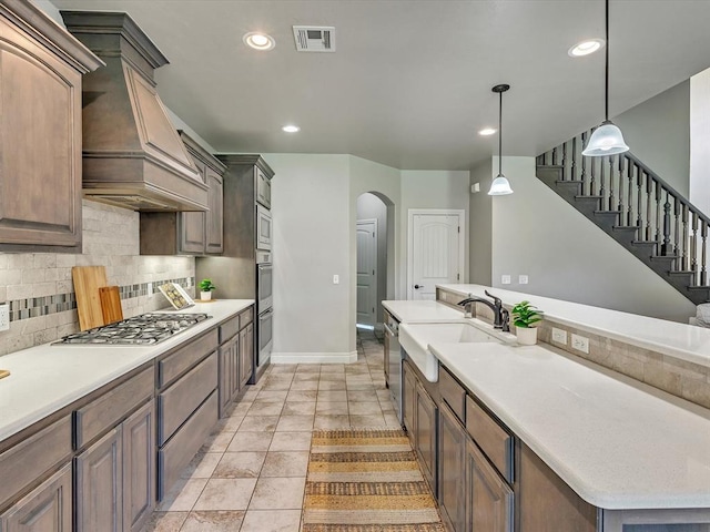10740 Starboard Way, Edmond, OK 73025 - kitchen with stainless steel appliances, premium range hood, arched walkways, decorative backsplash, and light countertops