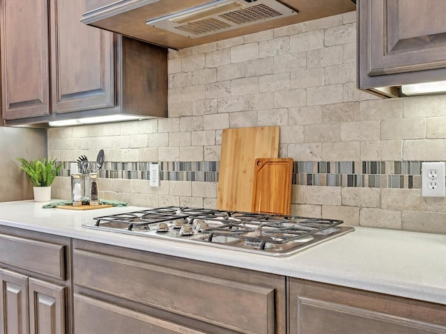10740 Starboard Way, Edmond, OK 73025 - kitchen with light countertops, stainless steel gas cooktop, backsplash, and range hood