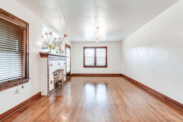 1502 NW 39th St, Oklahoma City, OK 73118 - unfurnished living room with a chandelier, a brick fireplace, baseboards, and wood finished floors