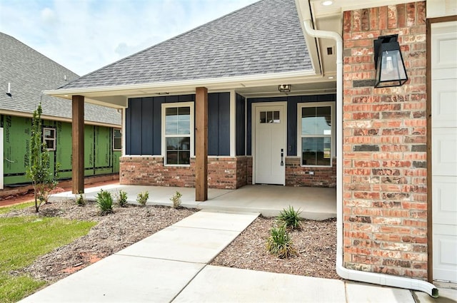 10412 SW 49th St, Mustang, OK 73064 - view of exterior entry featuring a porch, roof with shingles, board and batten siding, and brick siding