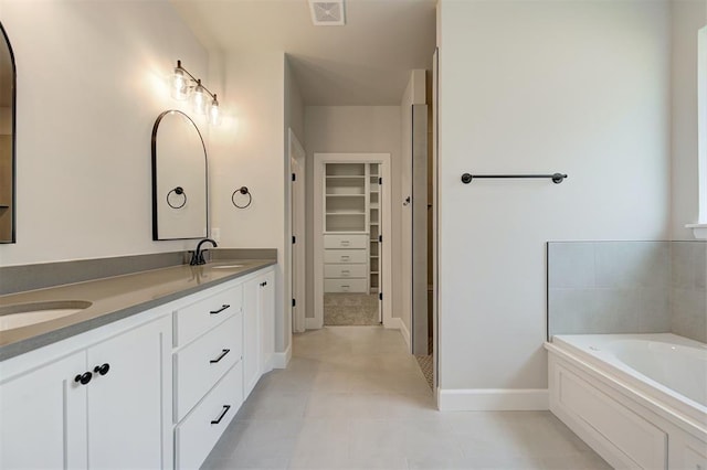 10412 SW 49th St, Mustang, OK 73064 - bathroom featuring double vanity, a spacious closet, a garden tub, baseboards, and tile patterned flooring