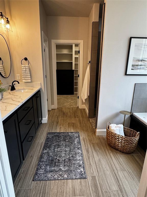 10421 SW 50th St, Mustang, OK 73064 - full bath featuring wood finished floors, double vanity, a tub, and a spacious closet