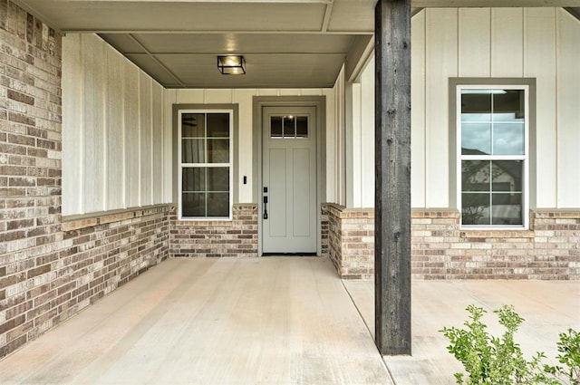 10440 SW 50th St, Mustang, OK 73064 - doorway to property with board and batten siding, brick siding, and a porch