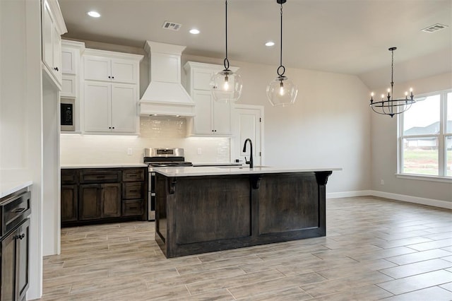 10440 SW 50th St, Mustang, OK 73064 - kitchen with stainless steel range oven, custom exhaust hood, light countertops, a chandelier, and lofted ceiling