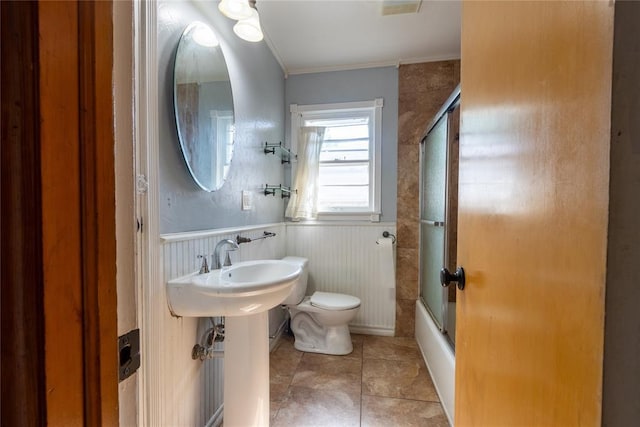 3701 NW 18th St, Oklahoma City, OK 73107 - full bath with toilet, a wainscoted wall, crown molding, tile patterned flooring, and shower / bath combination with glass door
