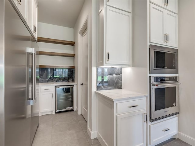 1116 Gateway Bridge Rd, Edmond, OK 73034 - kitchen with built in appliances, beverage cooler, decorative backsplash, and white cabinetry