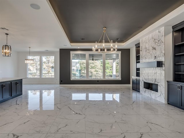 1117 Falls Bridge Ct, Edmond, OK 73034 - kitchen featuring a chandelier, a high end fireplace, built in shelves, and a raised ceiling