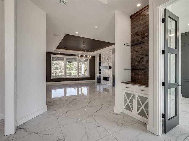 1117 Falls Bridge Ct, Edmond, OK 73034 - unfurnished living room featuring light marble finish floors, baseboards, a chandelier, recessed lighting, and a raised ceiling