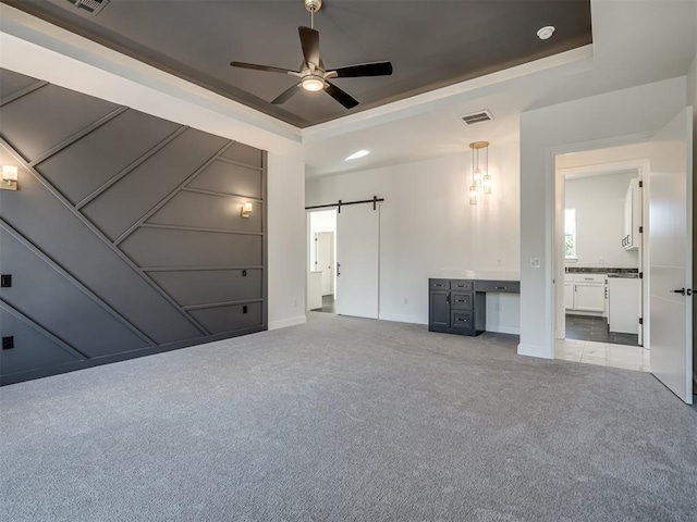 1117 Falls Bridge Ct, Edmond, OK 73034 - unfurnished bedroom featuring a tray ceiling, light colored carpet, baseboards, a barn door, and connected bathroom