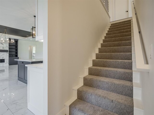 1117 Falls Bridge Ct, Edmond, OK 73034 - stairway featuring marble tiled flooring, a chandelier, and a high end fireplace