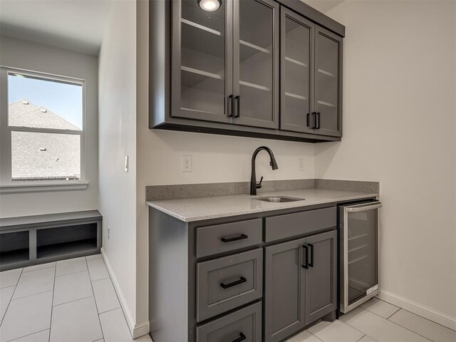 1117 Falls Bridge Ct, Edmond, OK 73034 - bar featuring a sink, beverage cooler, light tile patterned flooring, and baseboards