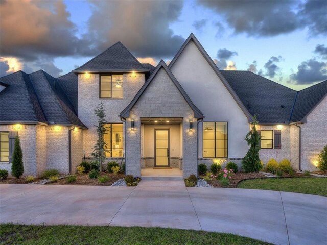 1117 Falls Bridge Ct, Edmond, OK 73034 - french country home with roof with shingles, brick siding, and stone siding