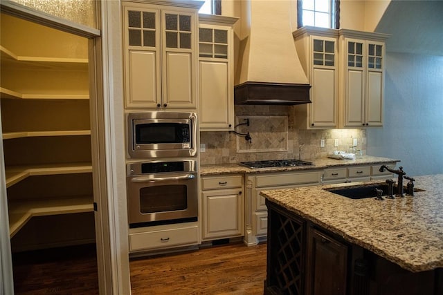 3176 E 146th Pl, Bixby, OK 74008 - kitchen with appliances with stainless steel finishes, premium range hood, a sink, dark wood-type flooring, and backsplash