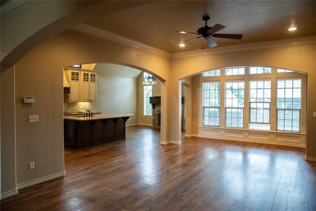 3176 E 146th Pl, Bixby, OK 74008 - unfurnished living room with ornamental molding, a ceiling fan, dark wood-style flooring, arched walkways, and baseboards