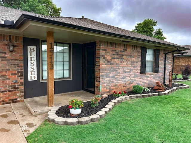 1913 Linwood St, Weatherford, OK 73096 - view of exterior entry featuring brick siding, a lawn, and roof with shingles