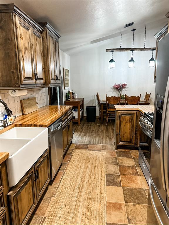 1913 Linwood St, Weatherford, OK 73096 - kitchen with a sink, appliances with stainless steel finishes, tasteful backsplash, butcher block counters, and pendant lighting