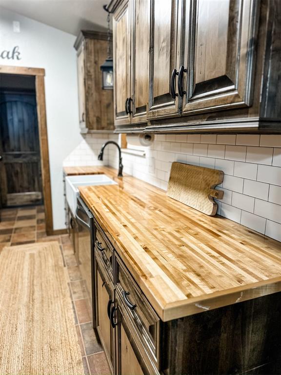 1913 Linwood St, Weatherford, OK 73096 - kitchen featuring wood counters, a sink, decorative backsplash, and dark brown cabinets