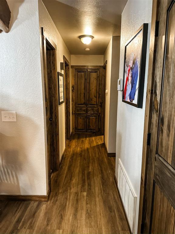 1913 Linwood St, Weatherford, OK 73096 - hall with dark wood-type flooring, baseboards, a textured wall, and a textured ceiling