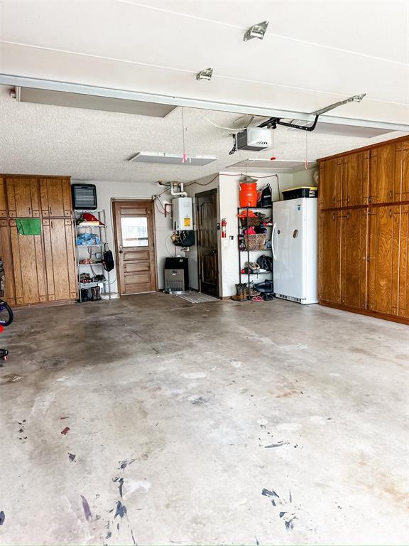 1913 Linwood St, Weatherford, OK 73096 - garage featuring freestanding refrigerator and a garage door opener
