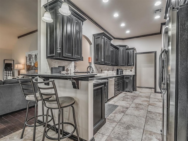 14512 Briarcliff St, Oklahoma City, OK 73170 - kitchen with stainless steel appliances, crown molding, decorative backsplash, a kitchen bar, and dark cabinets