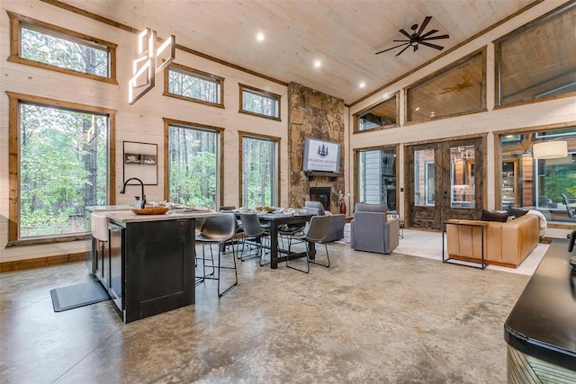 166 Morning Berry Trl, Broken Bow, OK 74728 - kitchen with finished concrete flooring, wooden ceiling, open floor plan, a towering ceiling, and wooden walls