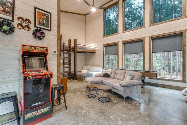 166 Morning Berry Trl, Broken Bow, OK 74728 - living room featuring wooden walls, ceiling fan, a high ceiling, concrete floors, and wood ceiling