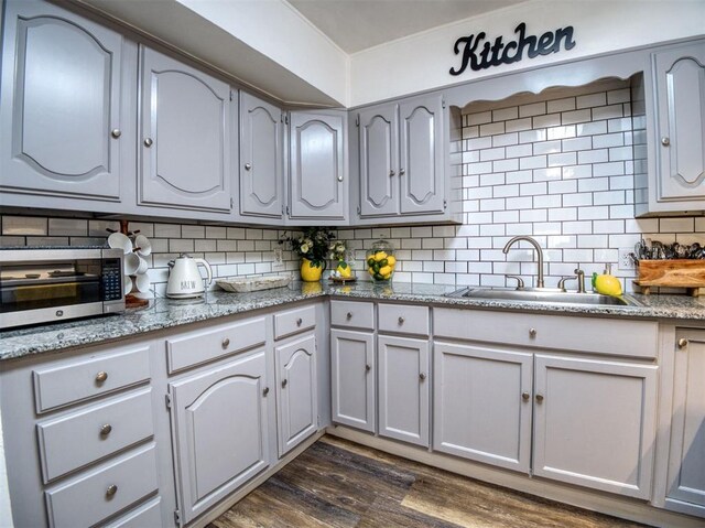3109 SW 45th St, Oklahoma City, OK 73119 - kitchen with a sink, dark wood-type flooring, decorative backsplash, and stainless steel microwave
