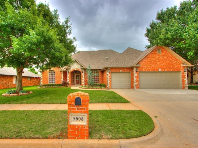 5608 NW 103rd St, Oklahoma City, OK 73162 - view of front of house featuring brick siding, a garage, driveway, a front yard, and roof with shingles