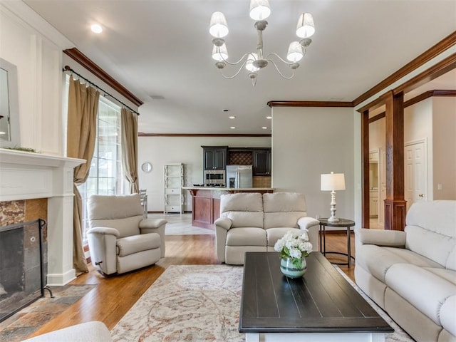 5608 NW 103rd St, Oklahoma City, OK 73162 - living room featuring crown molding, a chandelier, light wood-style flooring, a high end fireplace, and baseboards