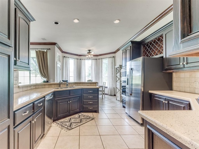 5608 NW 103rd St, Oklahoma City, OK 73162 - kitchen with stainless steel appliances, a sink, crown molding, tasteful backsplash, and a peninsula