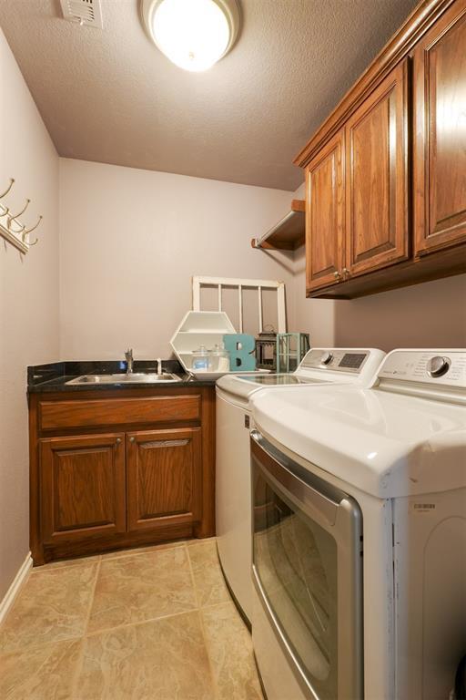 1401 Berkshire Pl, Shawnee, OK 74804 - washroom featuring separate washer and dryer, cabinet space, light tile patterned floors, and baseboards