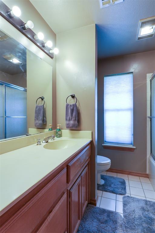 1811 N Bryan St, Shawnee, OK 74804 - bathroom with toilet, tile patterned floors, a shower with door, and vanity
