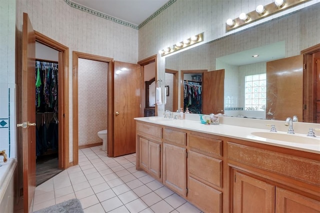 1811 N Bryan St, Shawnee, OK 74804 - full bathroom with wallpapered walls, double vanity, toilet, a spacious closet, and tile patterned floors