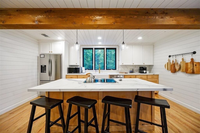 47 White Pine Rd, Broken Bow, OK 74728 - kitchen with wooden walls, light wood-type flooring, white cabinetry, light stone counters, and a wood ceiling with exposed beams