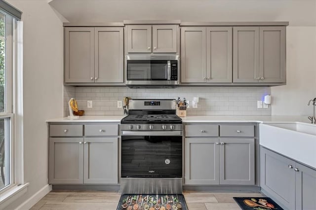 12905 NW 4th St, Yukon, OK 73099 - kitchen featuring stainless steel appliances, gray cabinetry, a sink, light wood-style flooring, and backsplash