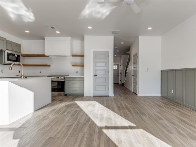 2812 Shoreridge Ave Unit 2814, Norman, OK 73072 - kitchen featuring open shelves, stainless steel appliances, a sink, wall chimney exhaust hood, and light wood finished floors