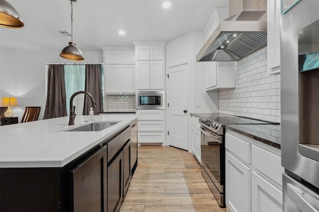 16315 SE 59th St, Choctaw, OK 73020 - kitchen with wall chimney exhaust hood, stainless steel appliances, a sink, light wood finished floors, and recessed lighting