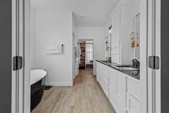 16315 SE 59th St, Choctaw, OK 73020 - bathroom featuring wood finished floors, double vanity, a freestanding bath, baseboards, and a walk in closet