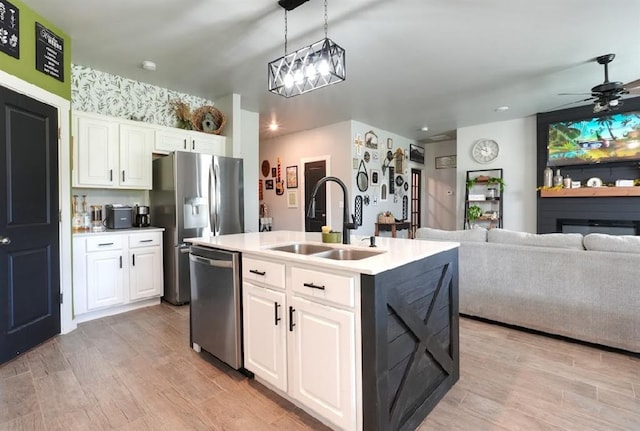 15963 Trail Head Rd, Mcloud, OK 74851 - kitchen featuring stainless steel appliances, a sink, an island with sink, white cabinets, and light wood-style flooring