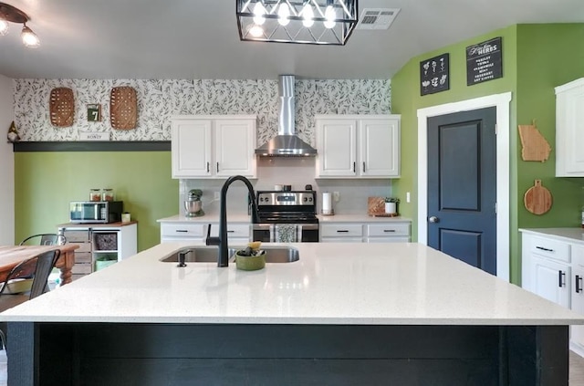 15963 Trail Head Rd, Mcloud, OK 74851 - kitchen with wall chimney exhaust hood, appliances with stainless steel finishes, a sink, an island with sink, and white cabinets
