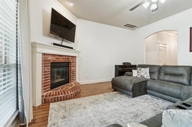 4605 NW 161st St, Edmond, OK 73013 - living area featuring arched walkways, ceiling fan, wood finished floors, crown molding, and a brick fireplace