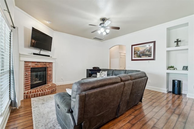 4605 NW 161st St, Edmond, OK 73013 - living room with arched walkways, built in features, wood finished floors, baseboards, and crown molding