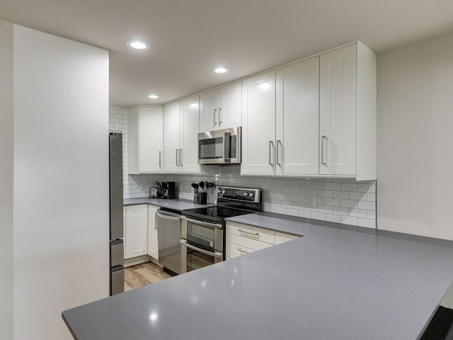 1110 Sherwood Ln Unit 223, Nichols Hills, OK 73116 - kitchen with stainless steel appliances, backsplash, white cabinetry, recessed lighting, and light wood-style flooring